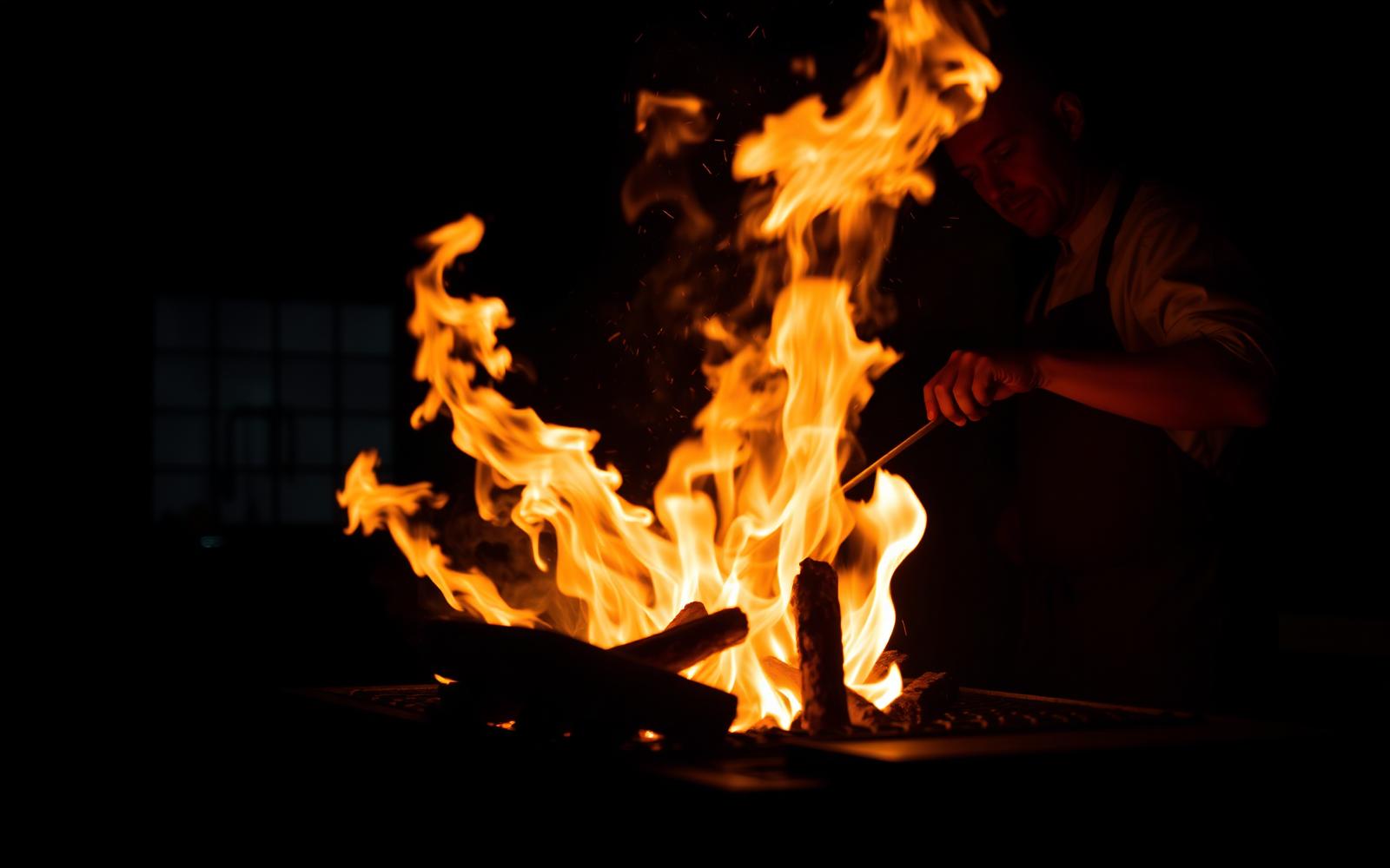 Chef tending an open wood fire in the NOIR kitchen